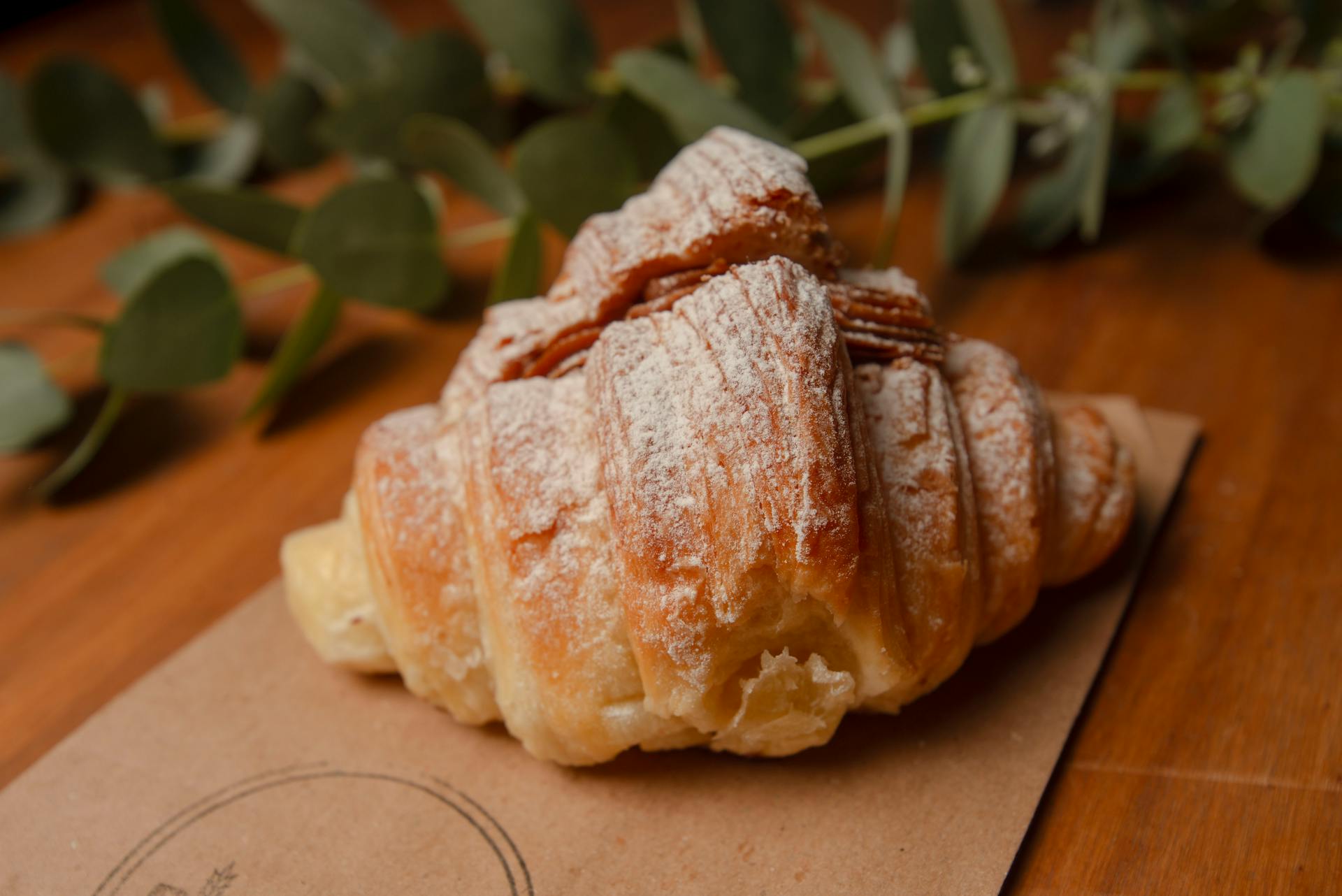 Freshly baked croissant topped with powdered sugar, showcasing delightful layers.