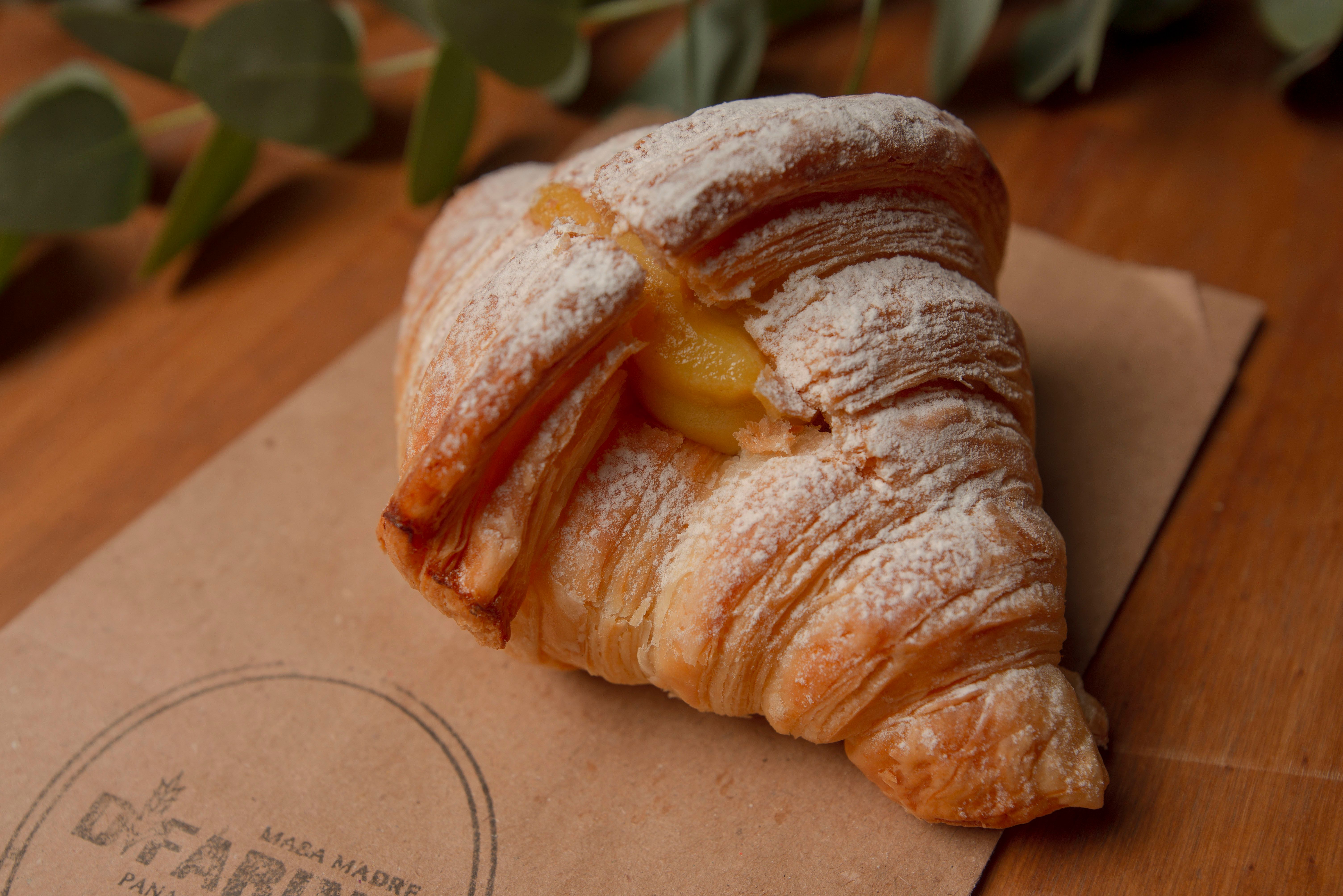 Croissant fraîchement cuit fourré à la crème anglaise sur une table rustique.