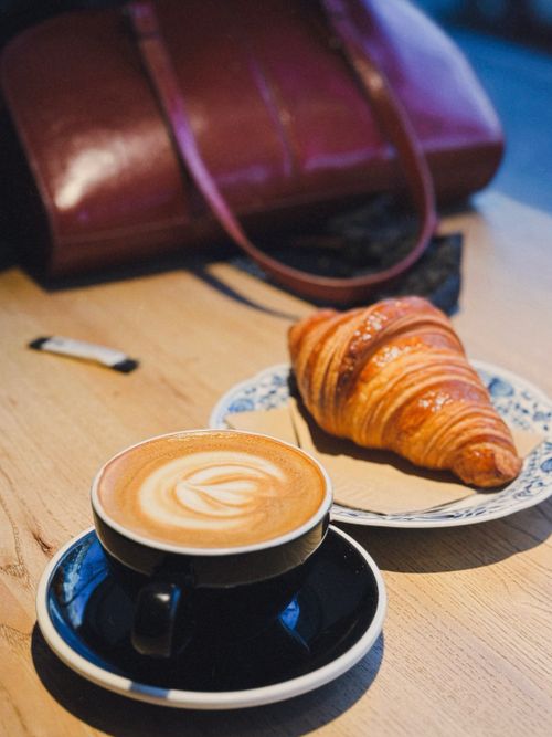 Free A warm latte and fresh croissant set in a cozy Berlin café, perfect for breakfast. Stock Photo