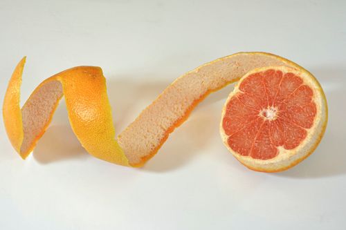 Free Sliced grapefruit with a creative spiral peel arrangement on a white background. Stock Photo