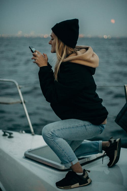 Woman Wearing Black Hoodie While Using Smartphone