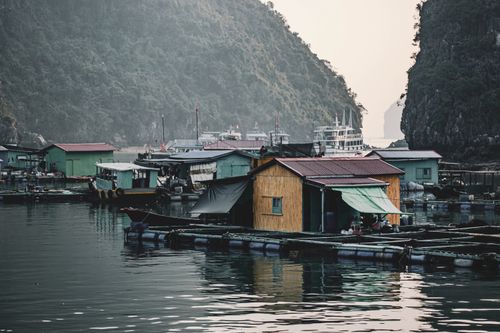 Free Floating fishing village in Ha Long Bay, Vietnam, surrounded by stunning limestone cliffs. Stock Photo