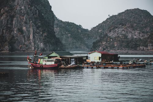 Free A traditional fishing boat and floating village in the serene waters of Ha Long Bay, Vietnam. Stock Photo