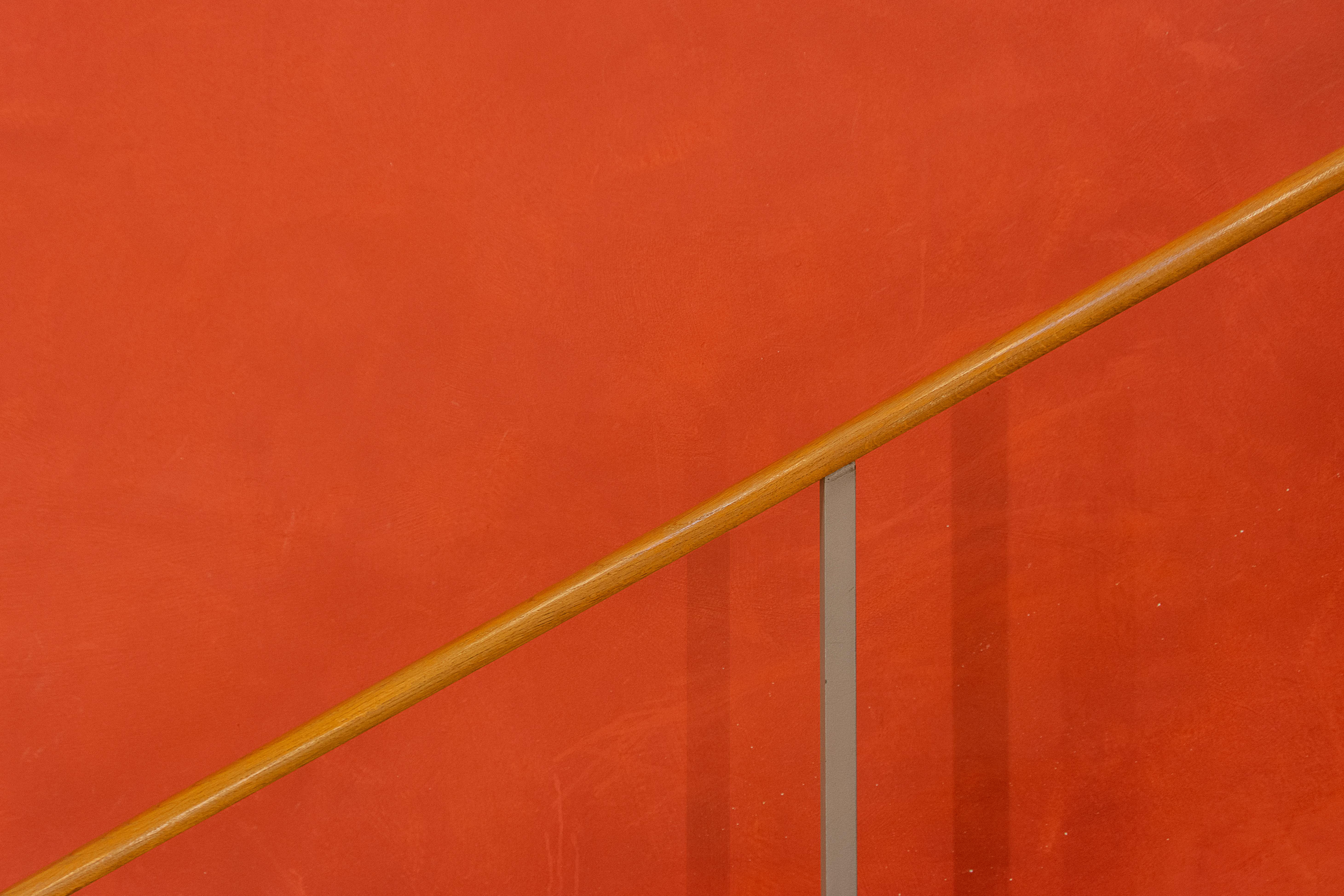gratis Een minimalistische rode muur met een eenvoudige houten leuning in een modern design. Stockfoto
