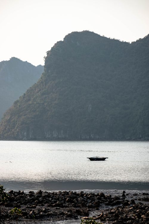 Free Peaceful lake scene with a boat and towering rocky mountains in the background. Stock Photo