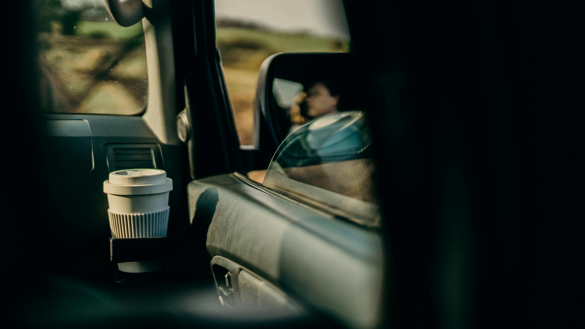 Eco-friendly travel with reusable cup and blurred reflections on a car ride.