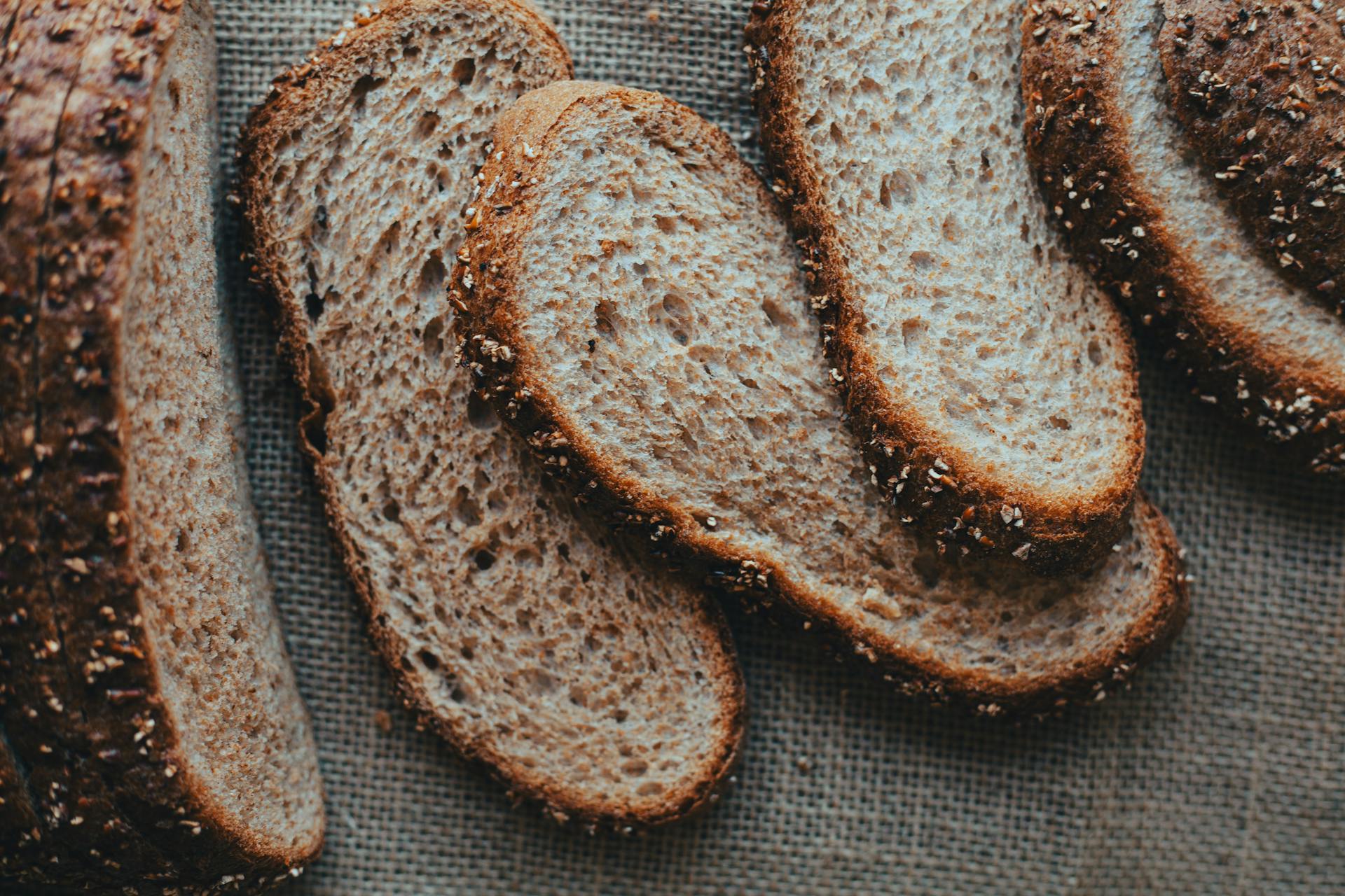 Close-up view of sliced whole grain bread on a textured burlap surface, perfect for bakery promotions.