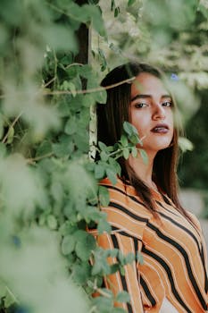一名身穿条纹服装的女子自信地在户外绿叶中摆姿势