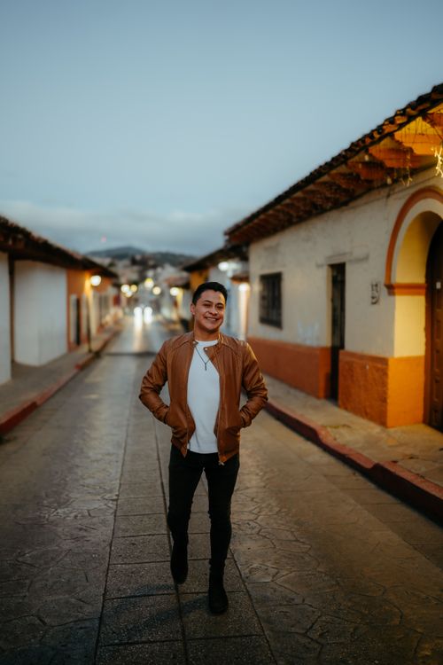 Free Man walking down a vibrant street in San Cristóbal, México at dusk. Stock Photo