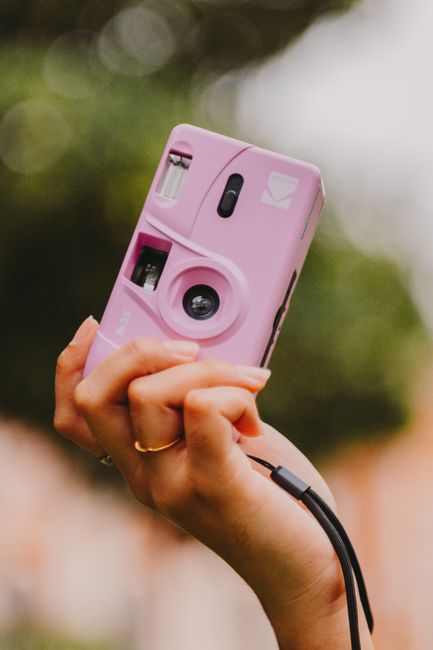 Hand holding a pink analog camera with bokeh background. Shot in Belém, Brazil.