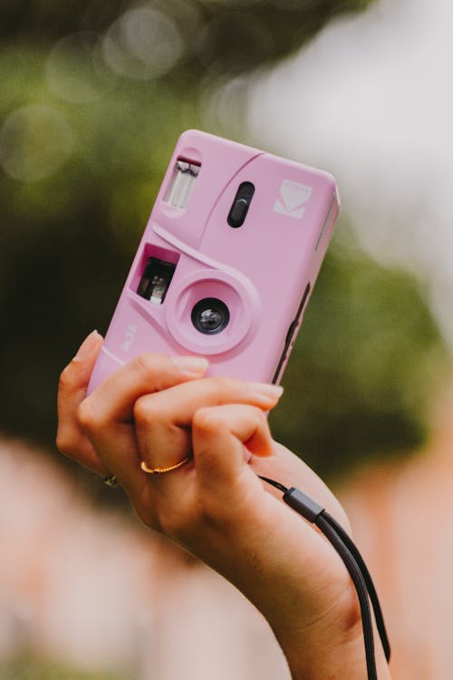 Free Hand holding a pink analog camera with bokeh background. Shot in Belém, Brazil. Stock Photo