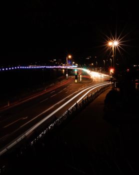 A captivating night scene of a city bridge with light trails from moving vehicles.