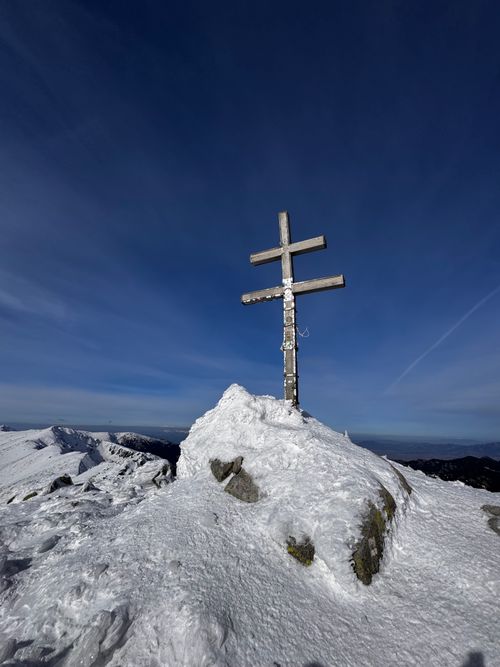 Free Triple-armed cross on a snowy mountain peak under clear blue sky in Slovakia's Low Tatras. Stock Photo