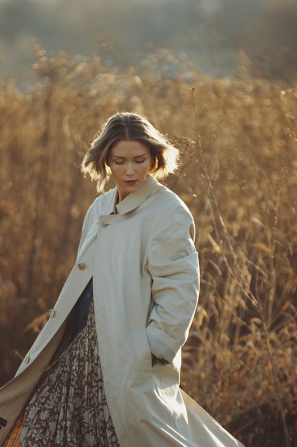 A serene woman in a flowing dress captured in golden autumn light outdoors.