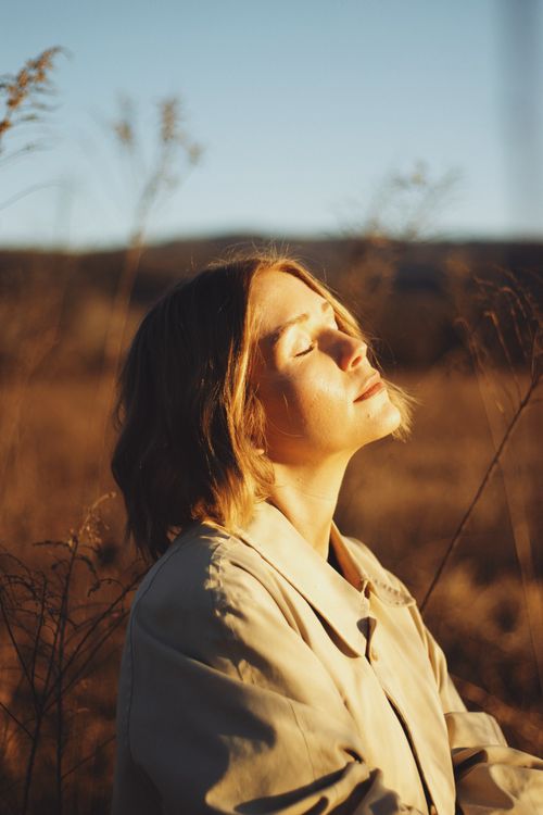 Free A woman embraces the warm glow of golden hour in a serene field in Brevard, NC. Stock Photo
