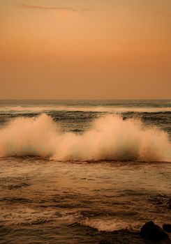 A beautiful sunset over crashing waves in Paia, Hawaii, creating a vibrant and serene ocean scene.