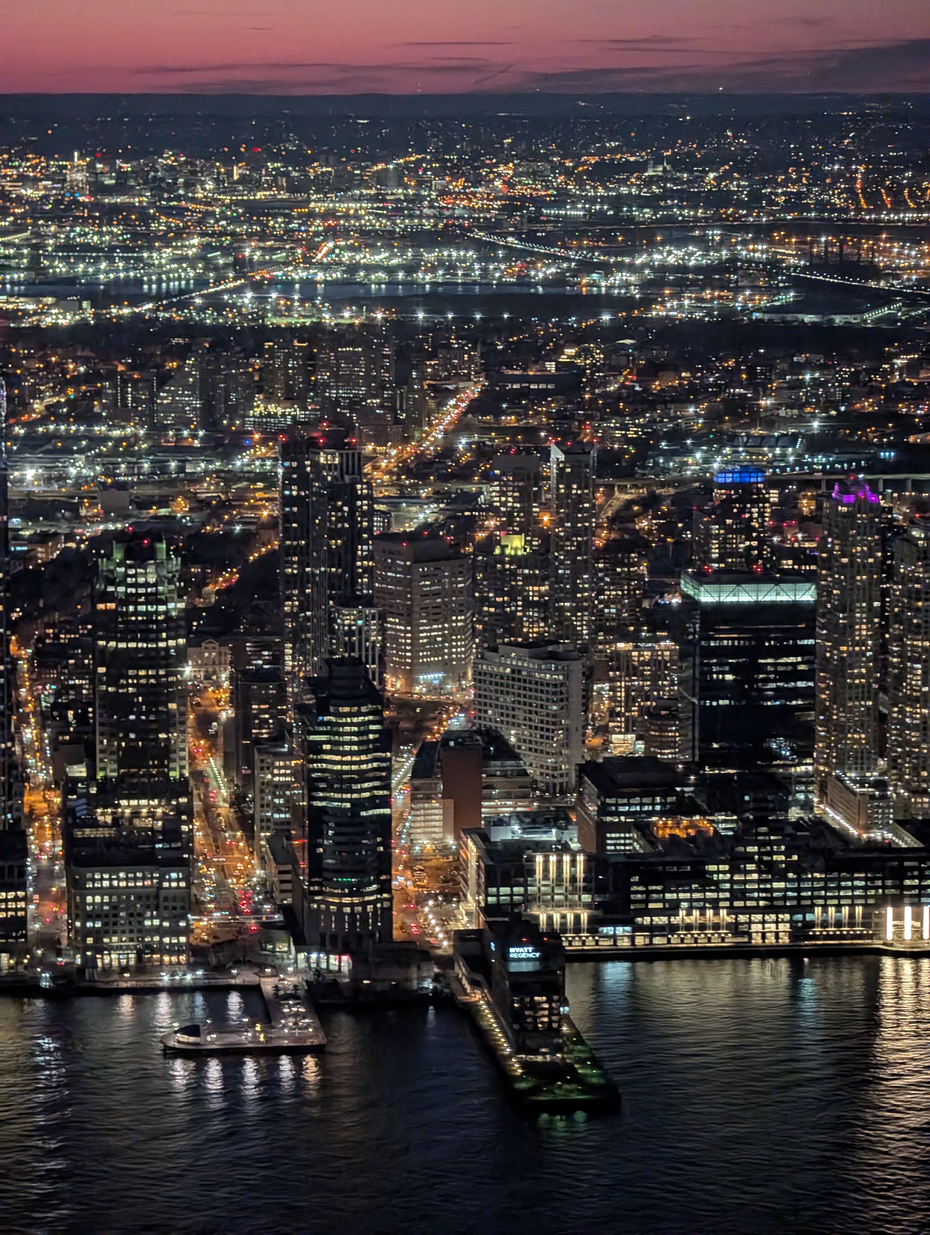 A breathtaking aerial view of a bustling cityscape at twilight, illuminated by city lights.