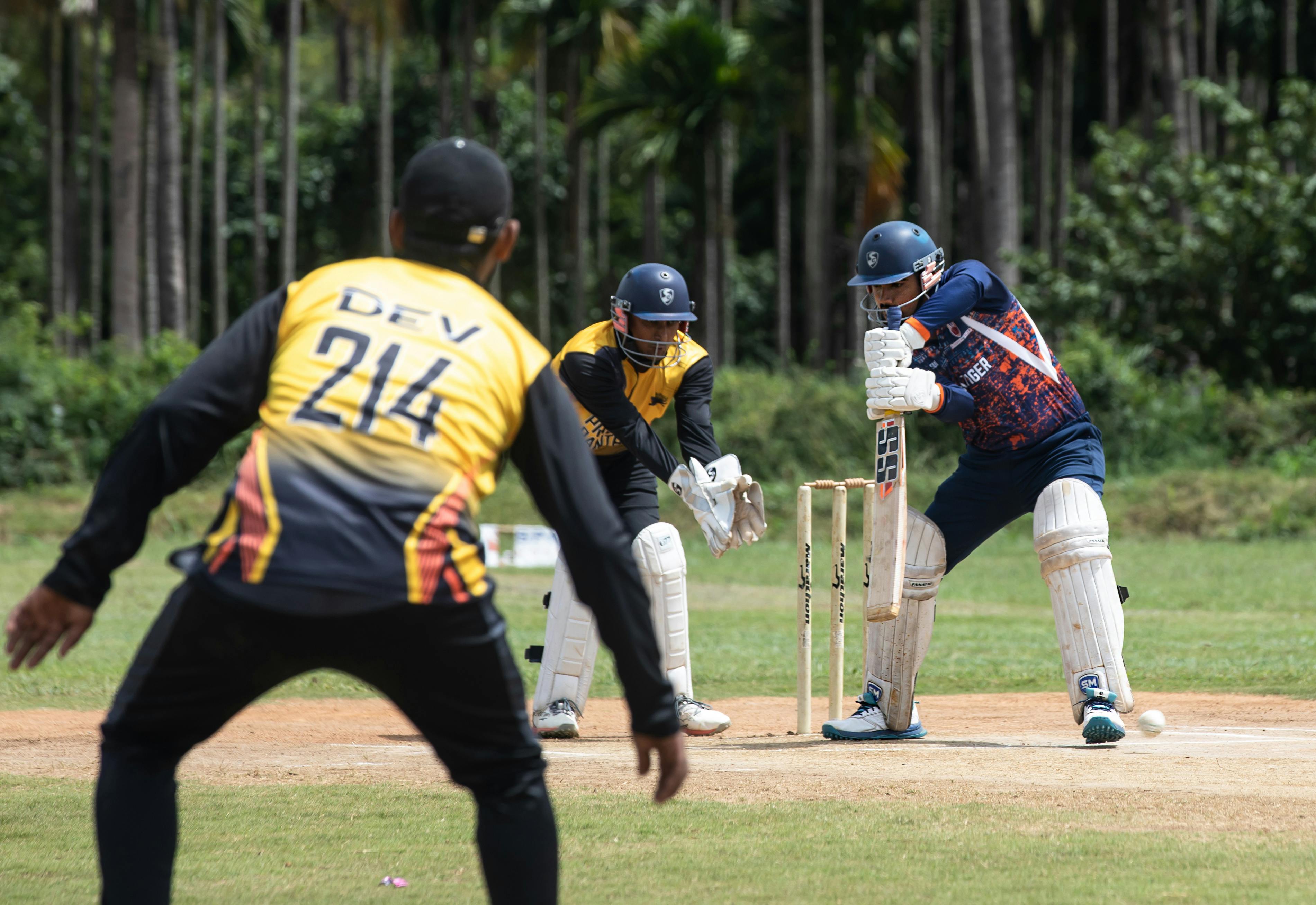 Dynamic cricket match scene with batsman, wicketkeeper, and fielder in action.