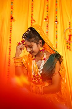 Smiling Indian bride in vibrant attire during traditional Haldi ceremony.