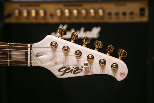 Detailed shot of guitar headstock with gold tuning pegs in front of amplifier.