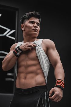 Fit man showcasing defined abs in a modern gym, highlighting strength and dedication.