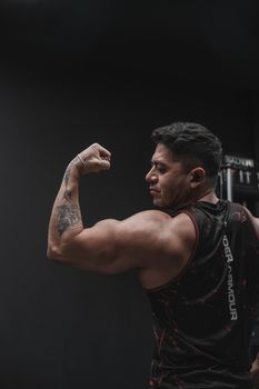 Strong man flexing bicep in a gym, showcasing strength and fitness.