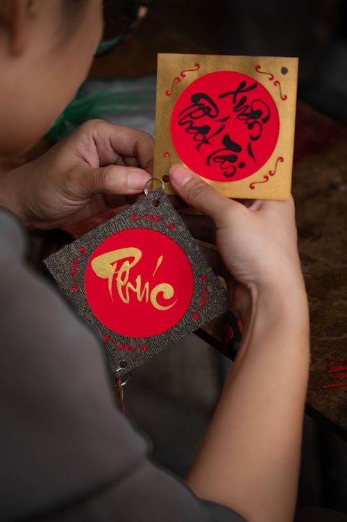 Free Hands holding decorative paper with artistic red symbols and designs. Stock Photo