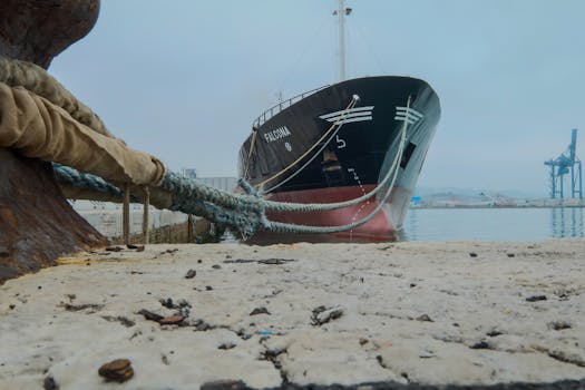 A striking image of a cargo ship docked at an industrial port with ropes securing it.