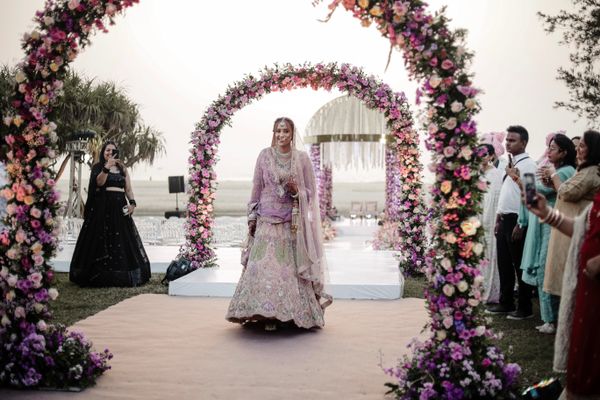 Indian bride beneath a floral wedding arch