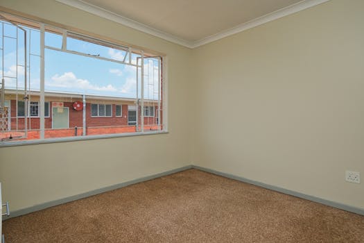 Sunlit empty room with a view of building exterior, perfect for real estate listings.