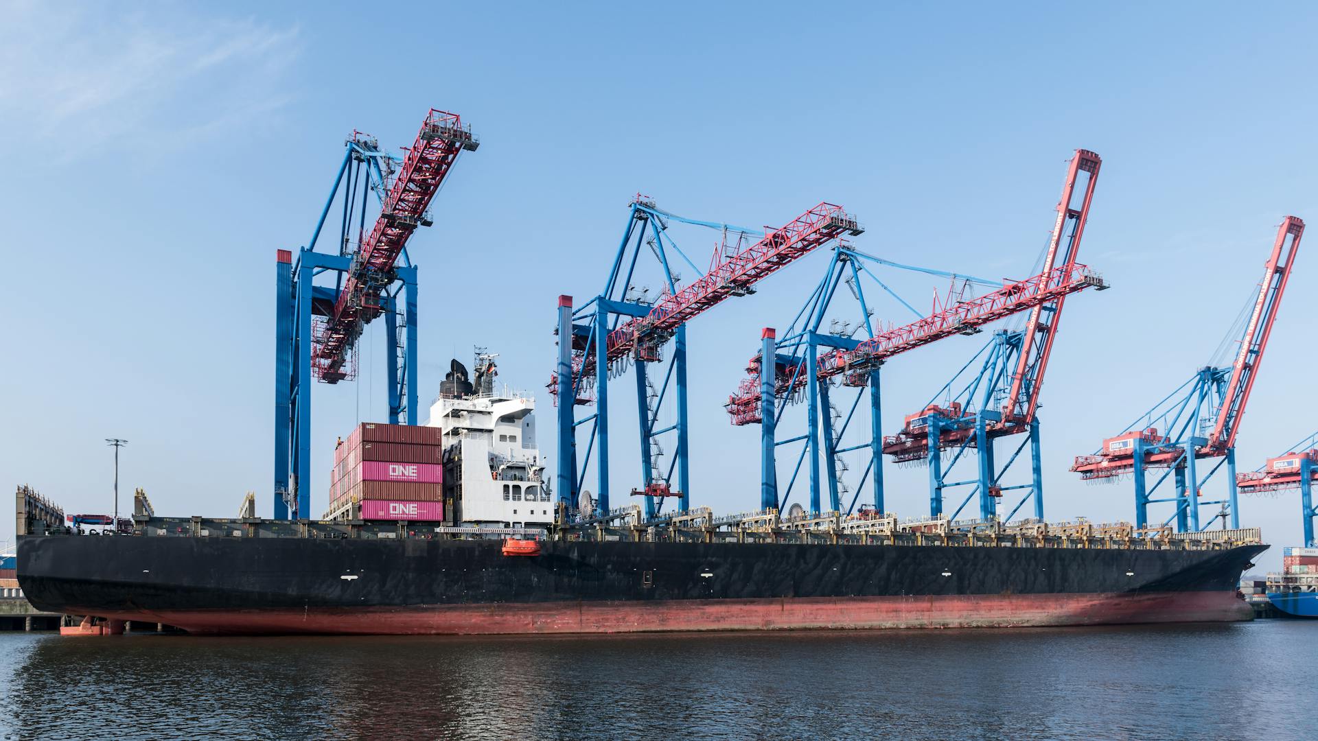 A large container ship docked with cranes, showcasing global trade in Hamburg Port.