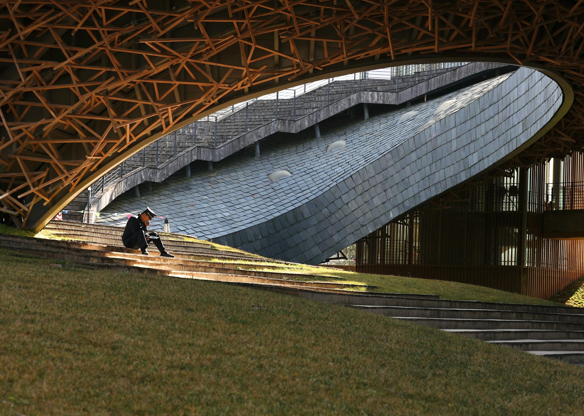 Person reading in tranquil architectural setting, unique structure.