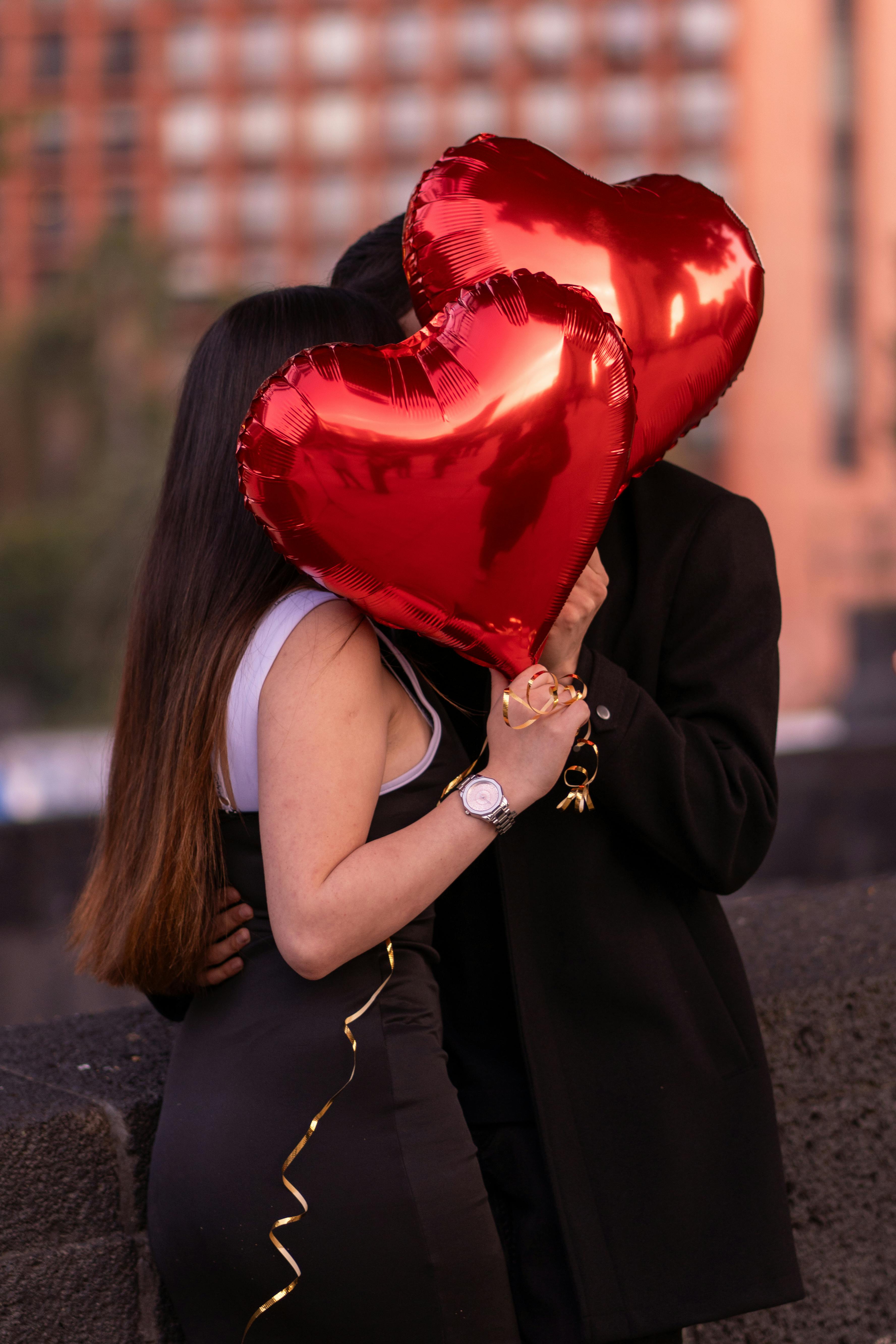 A couple shares a romantic moment with red heart balloons in Mexico City.