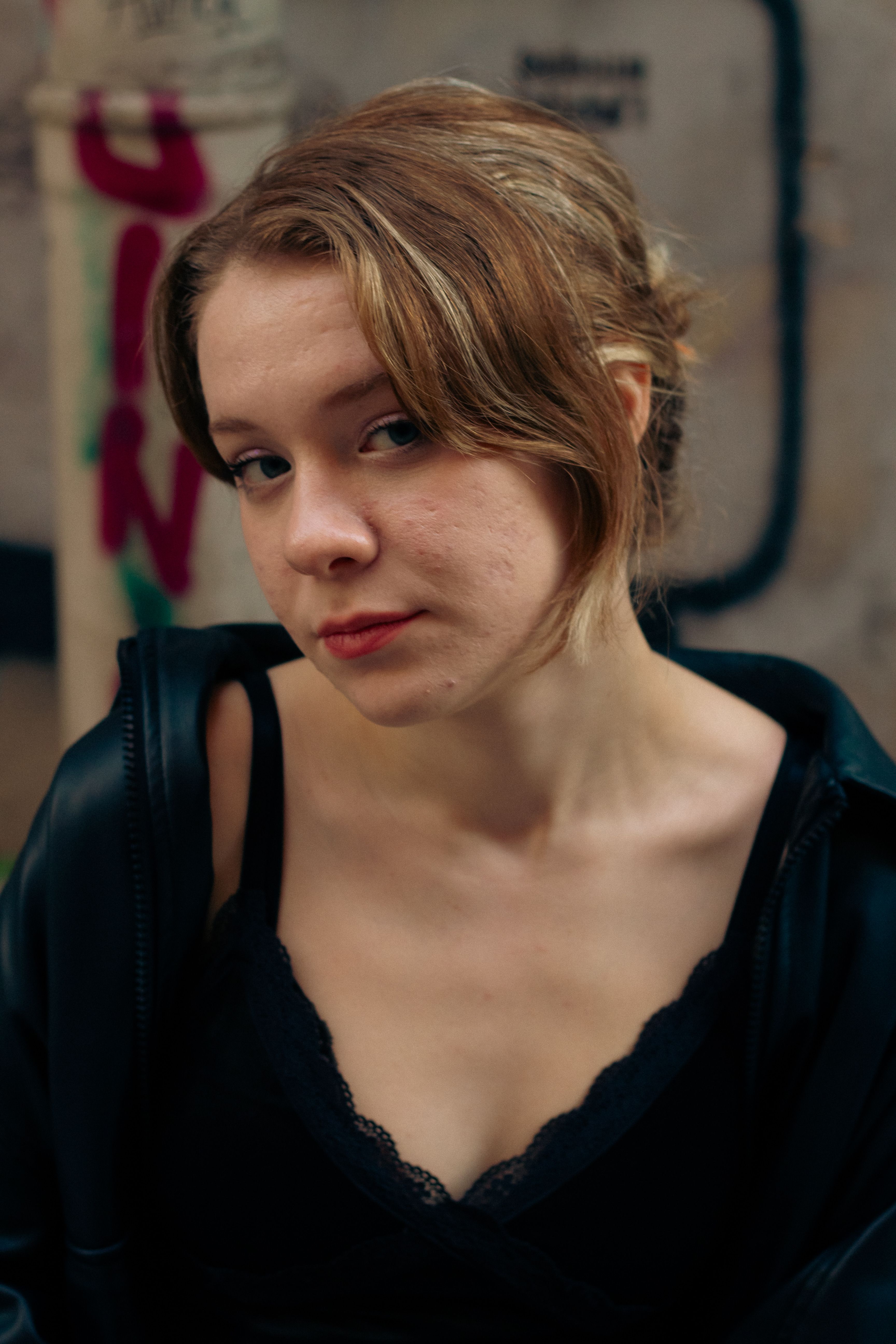 A thoughtful young woman poses in an urban backdrop, highlighting her natural expression.