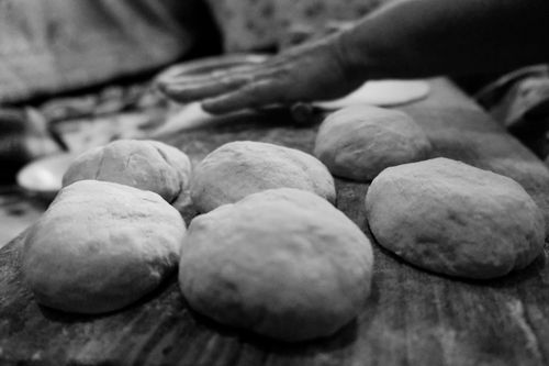 Free Artistic black and white shot of hand kneading dough for homemade bread on wooden surface. Stock Photo