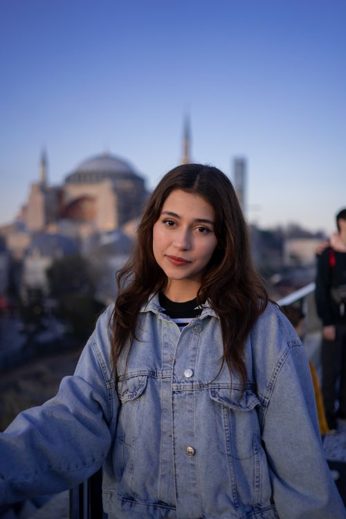 Free Portrait of a young woman with the Hagia Sophia in the background, captured at dusk. Stock Photo