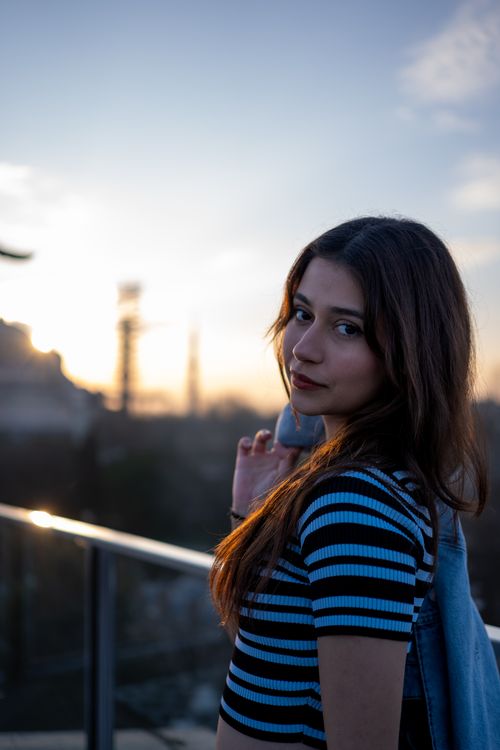 Free Woman on rooftop during sunset gazing over cityscape, creating a dramatic silhouette. Stock Photo