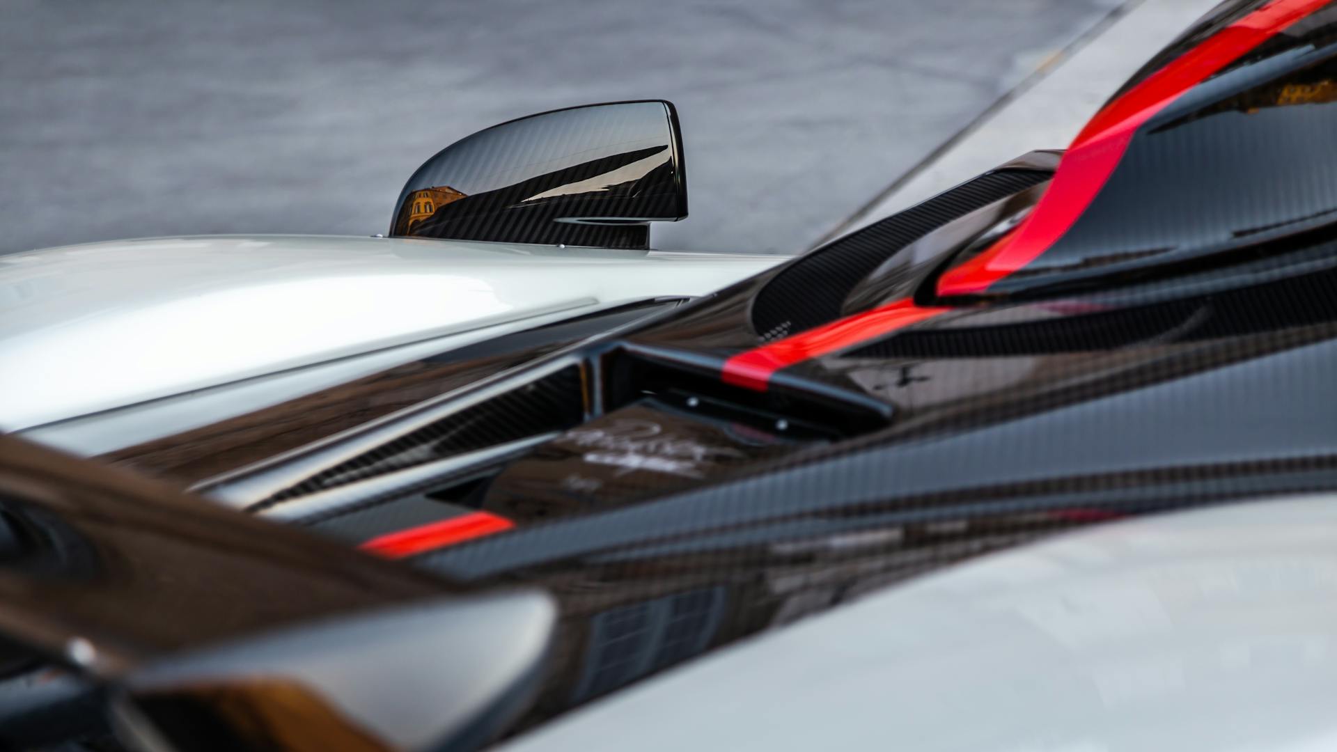 High-angle close-up of sleek supercar features with carbon fiber accents and aerodynamic design.