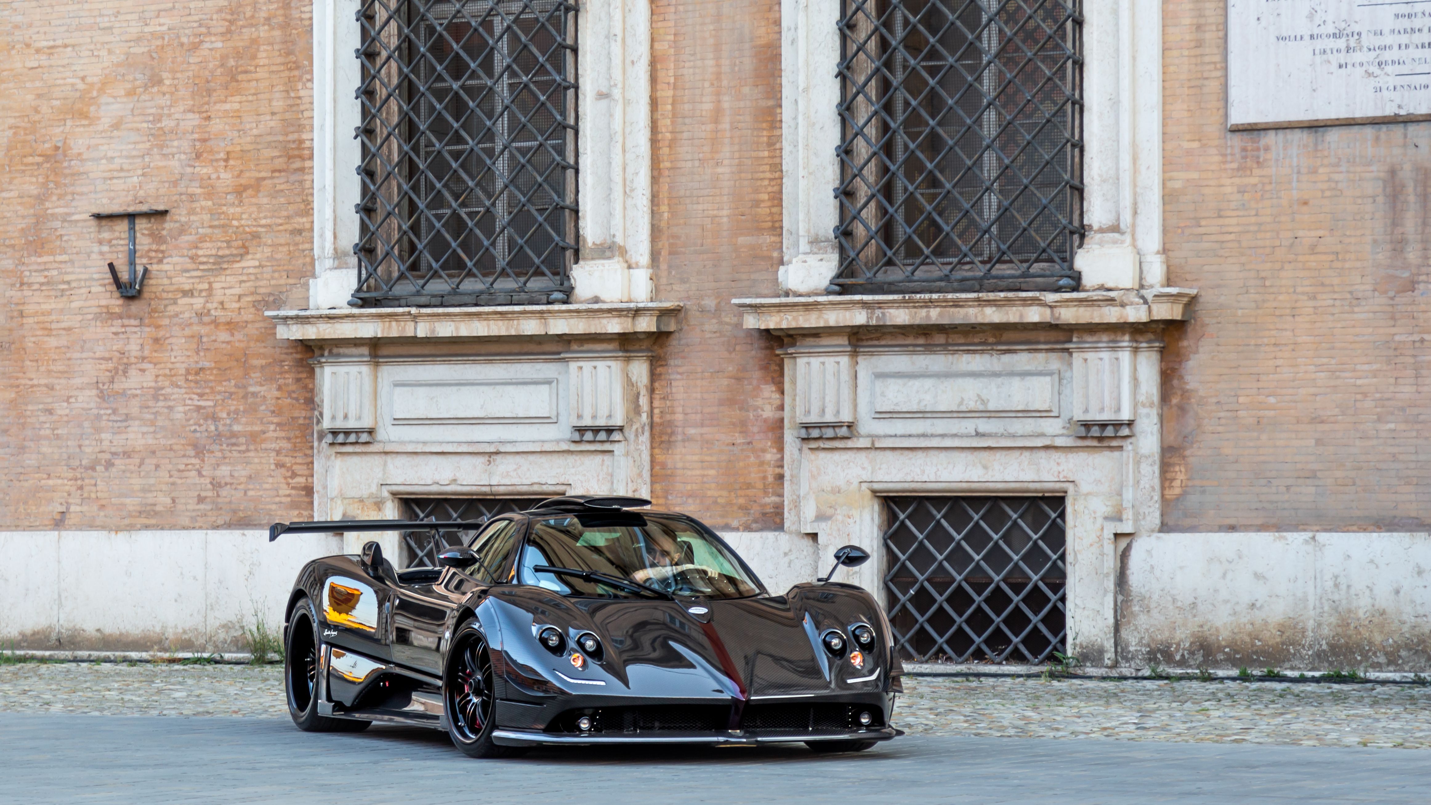 Sleek black supercar parked against historic urban architecture.