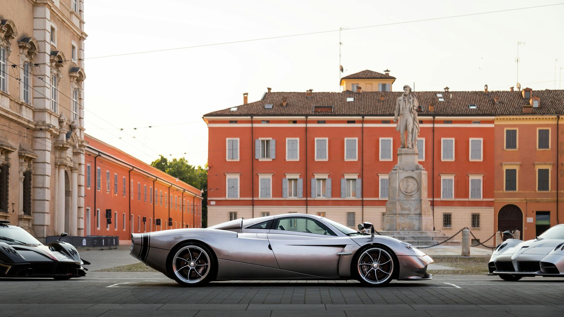 Sleek silver supercar parked in an elegant historic square, evoking luxury and style.