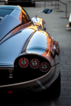 Close-up of a sleek, glossy hypercar at sunset capturing luxury and design.