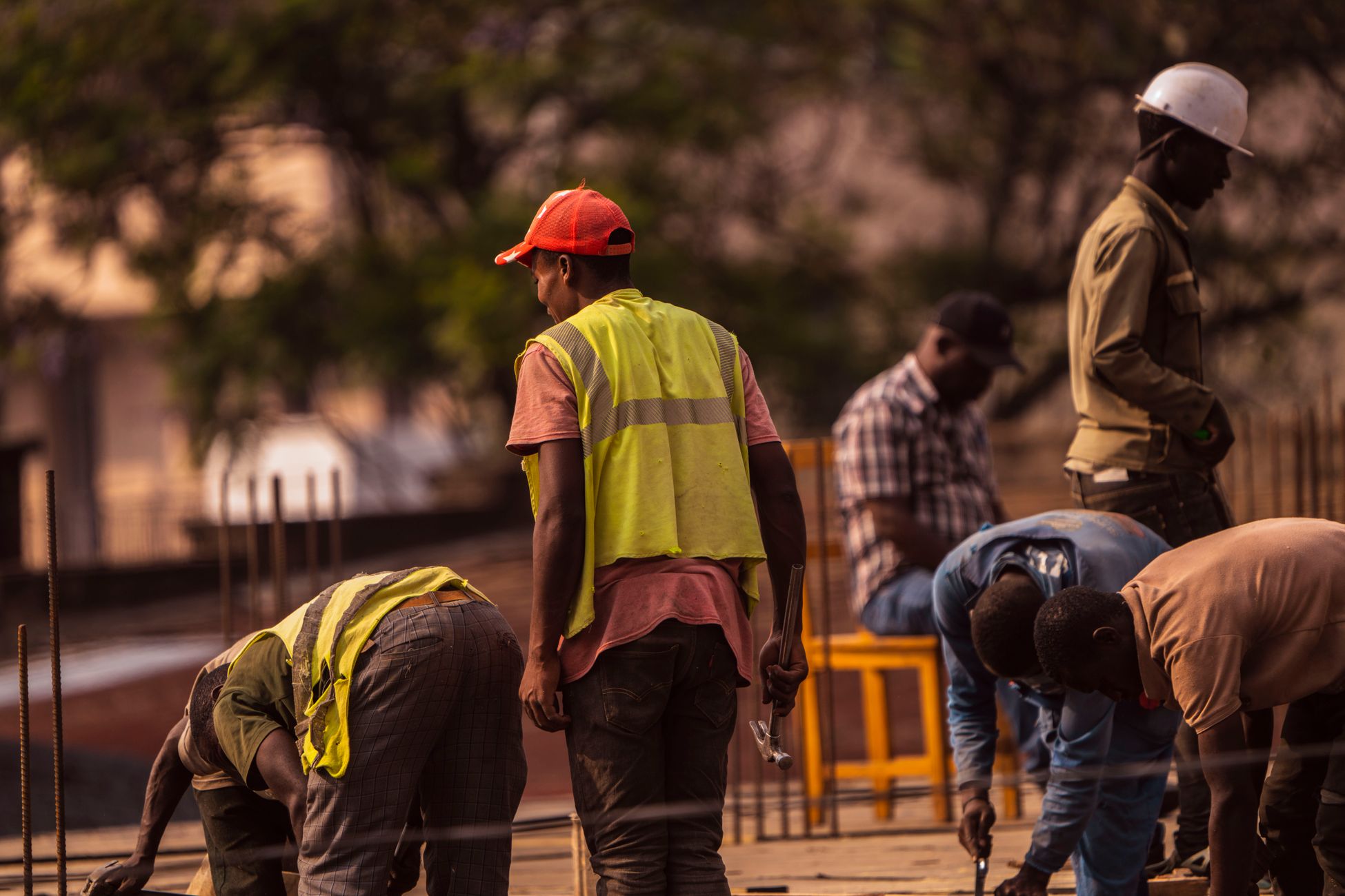 Group of male construction workers on site wearing safety gear during daytime.