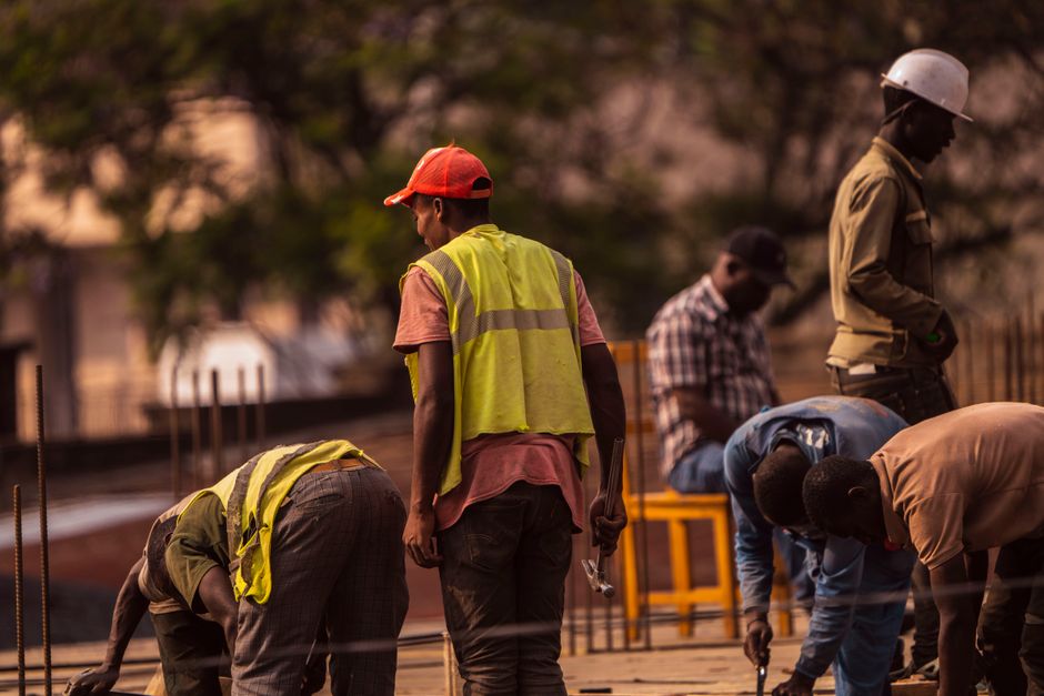 Grupo de trabajadores de la construcción varones en el lugar usando equipo de seguridad durante el día.