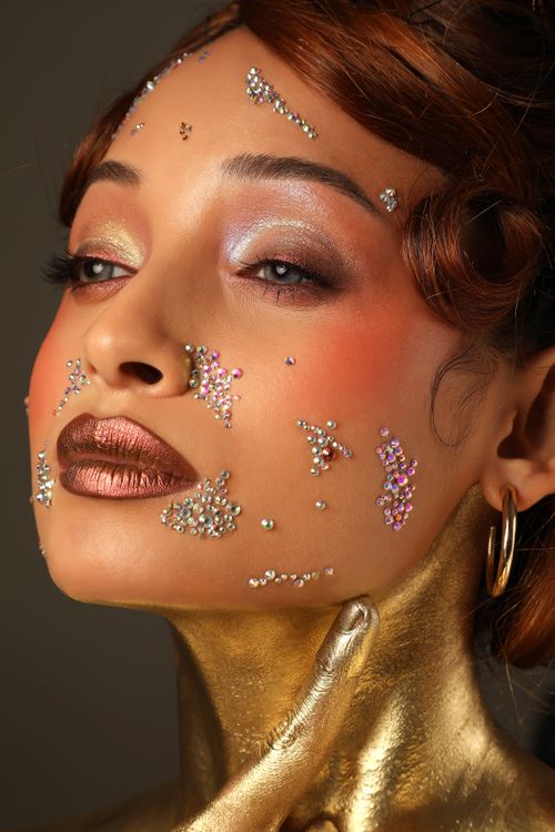 Free Artistic portrait of a woman with gold makeup and rhinestone embellishments, exuding elegance. Stock Photo