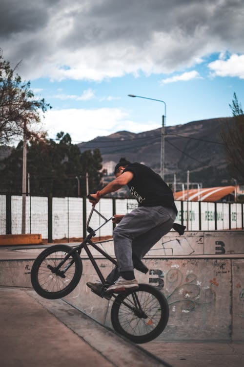 Hombre Vestido Con Camisa Negra Y Jeans Grises Montando Bmx Negro