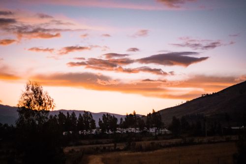 Free Beautiful sunset over a mountainous landscape creating a silhouette of trees and hills. Stock Photo