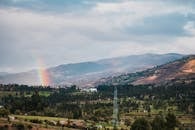 阴云密布的天空中，一道充满活力的彩虹穿过，与令人惊叹的山脉一同展现了大自然的美丽