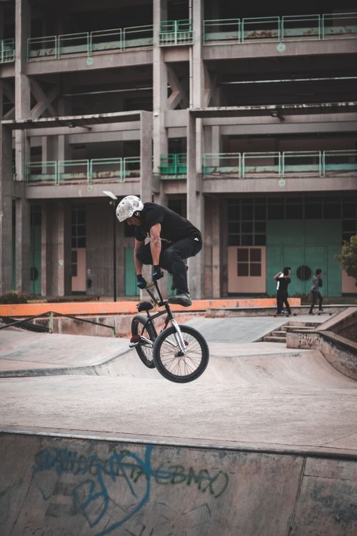 Free Skilled BMX rider executing a trick in a vibrant urban skate park environment. Perfect for urban sports themes. Stock Photo
