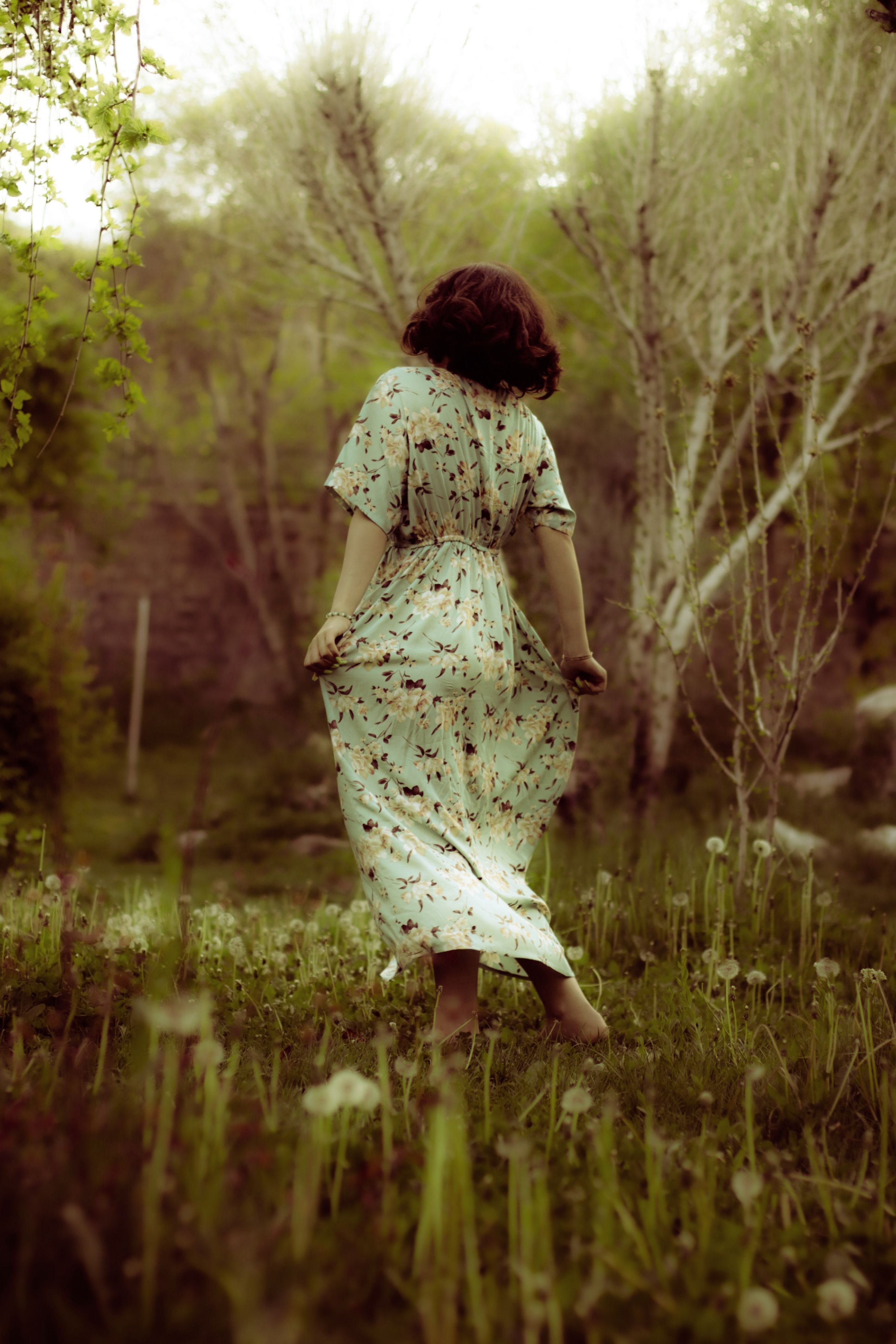 Woman in Floral Dress Strolling Through Green Meadow · Free Stock Photo