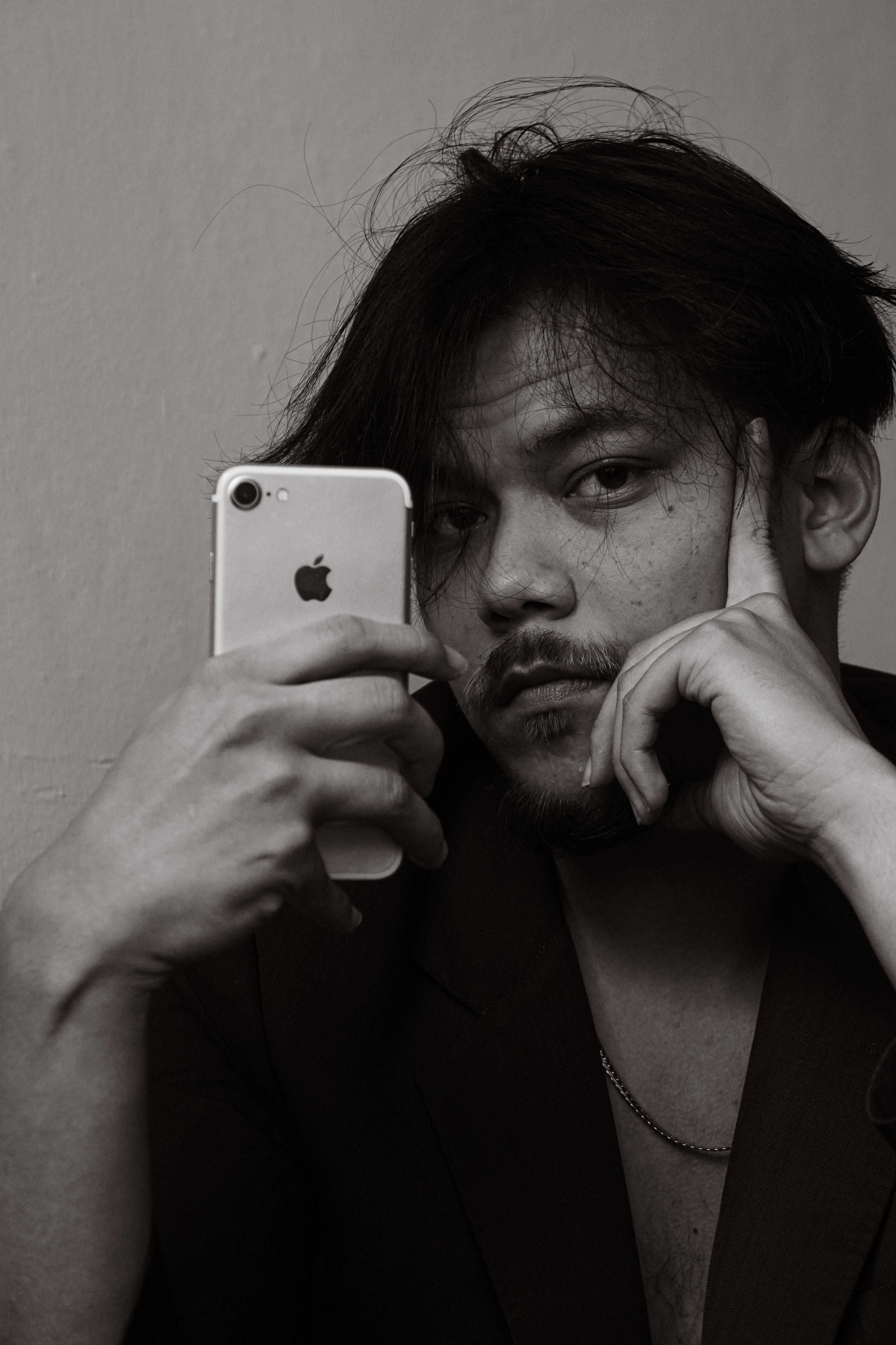 Moody black and white portrait of a man with smartphone reflection.